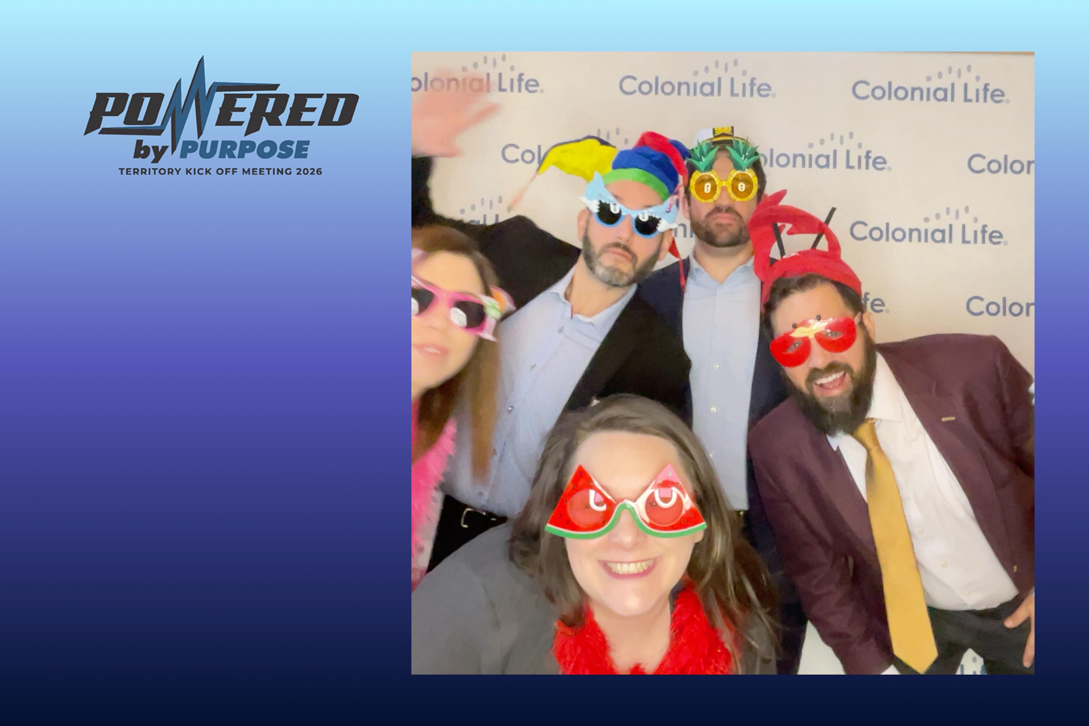 Group photo of five colleagues wearing party glasses and props